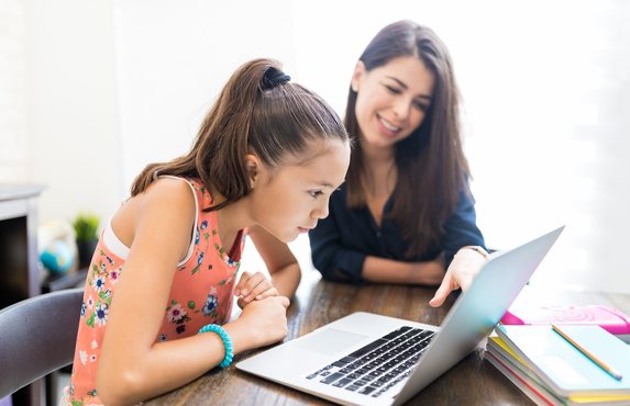 A teacher and pupil working together on a laptop